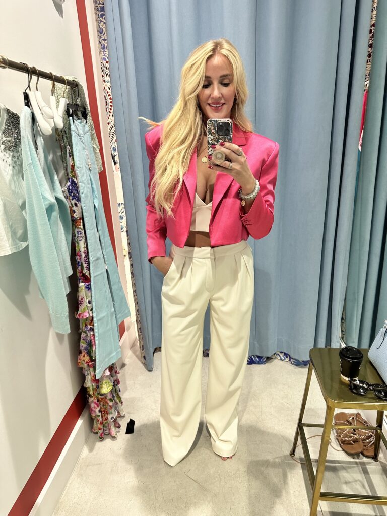 Jessica trying on an outfit for what to wear in Palm Beach. White Trouser pants, a white tank crop top with a hot pink cropped blazer