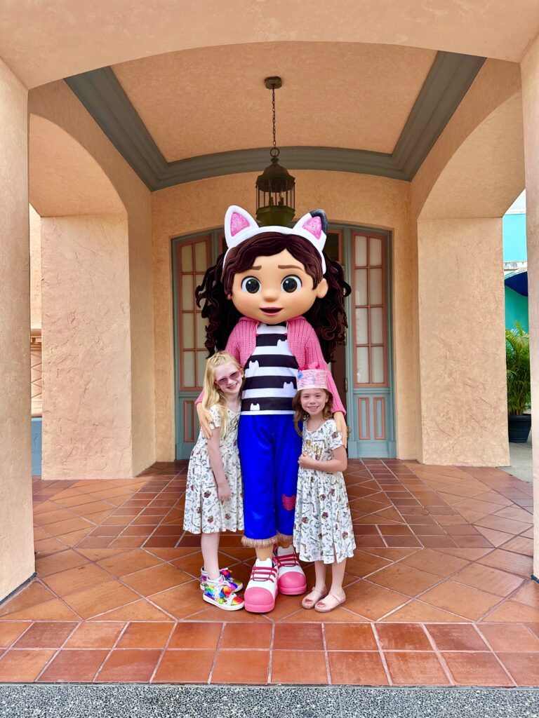 two girls posing with a Disney character wearing matching Harry Potter dresses